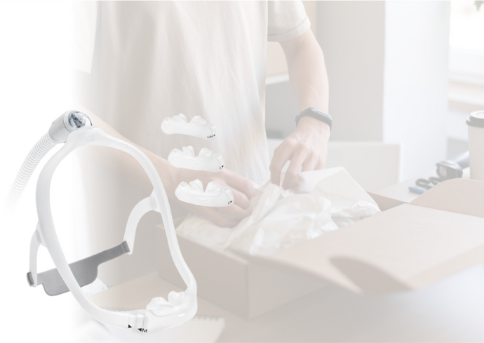 Person opening a box next to sleep apnea mask parts and equipment on a table.