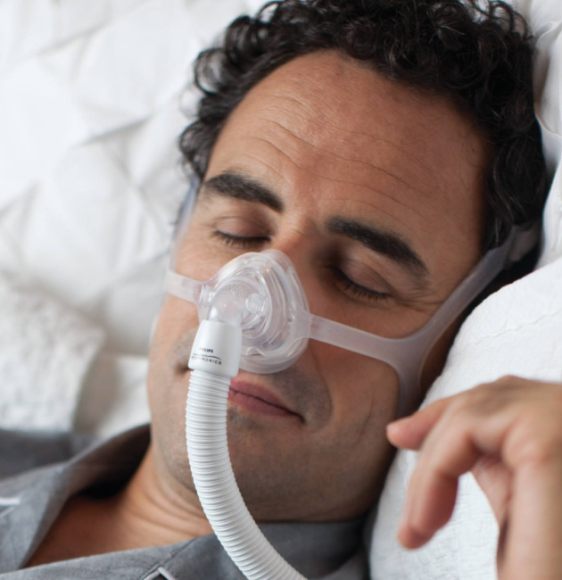 Man sleeping peacefully with a CPAP mask for sleep apnea.