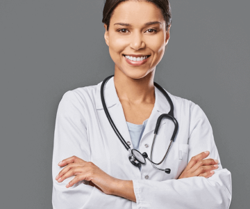 Smiling female doctor in a white coat with a stethoscope, standing confidently with arms crossed.