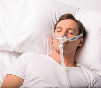 Man sleeping with nasal pillow CPAP mask.